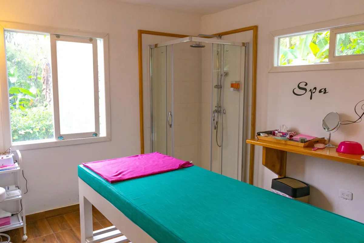 Treatment room with massage table and garden windows at Mandragora Spa, Mindo